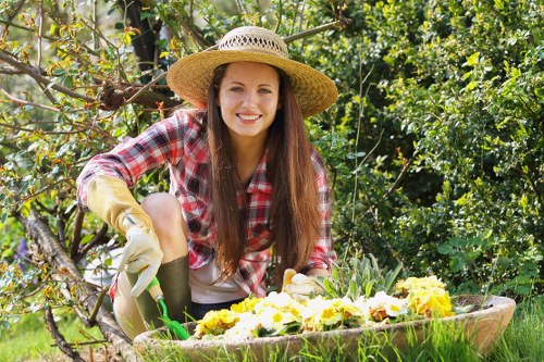 Gardener pruning overgrown shrubs during garden clearance.